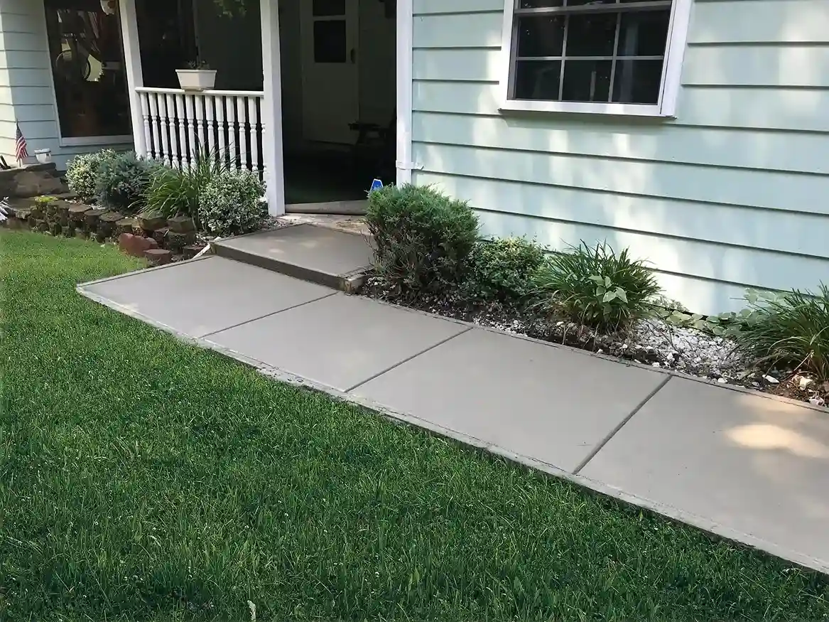 concrete walkway leading to a home's entrance, surrounded by green landscaping